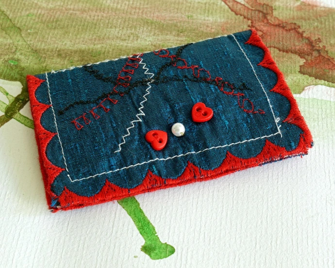 Handmade blue wallet with red trim and heart buttons